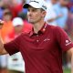 Justin Rose celebrating a made putt at the PGA Tour, wearing a red polo, white hat, and fist pumping in the air.