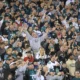 Eagles fans cheering in Lincoln Financial Field, with one fan in the center of the picture with his arms in the air wearing a grey hoodie with the Eagles logo in the center.